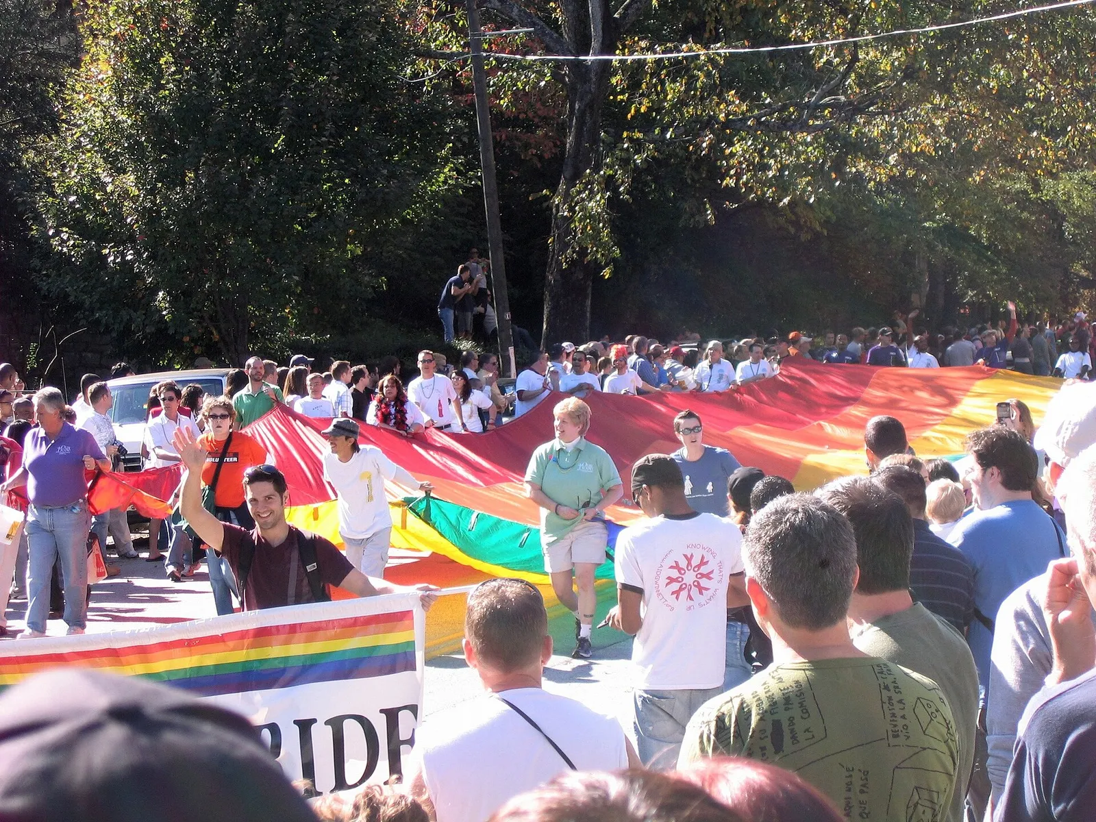 A large rainbow flag carried through a crowd