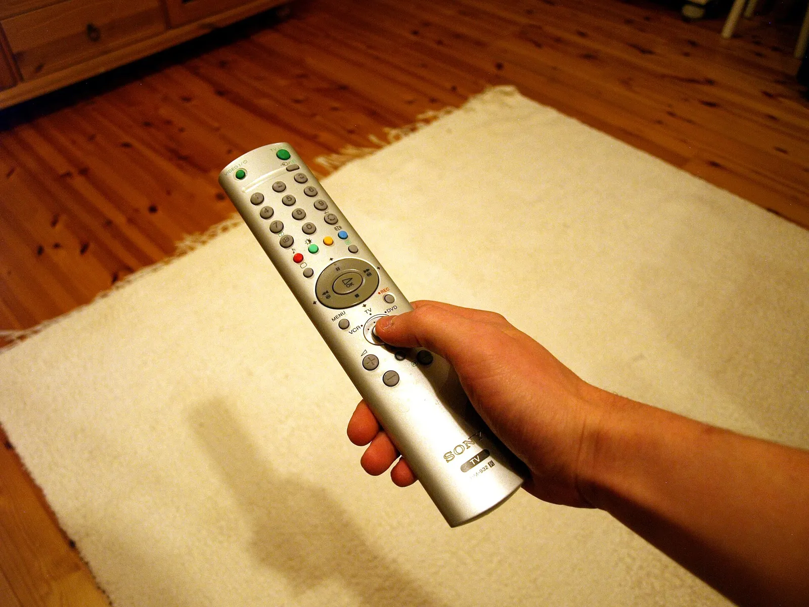 A hand holding a television remote control
