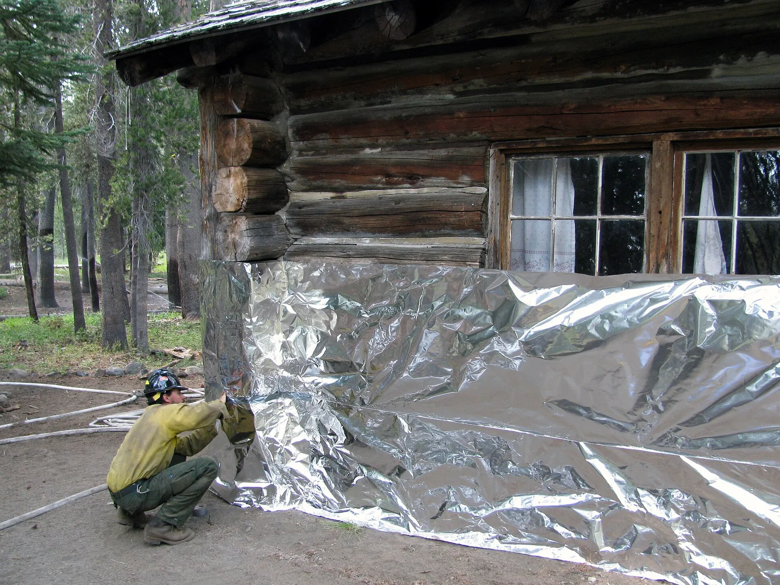 A firefighter wraps a cabin to protect it from embers and radiant heat (file image)