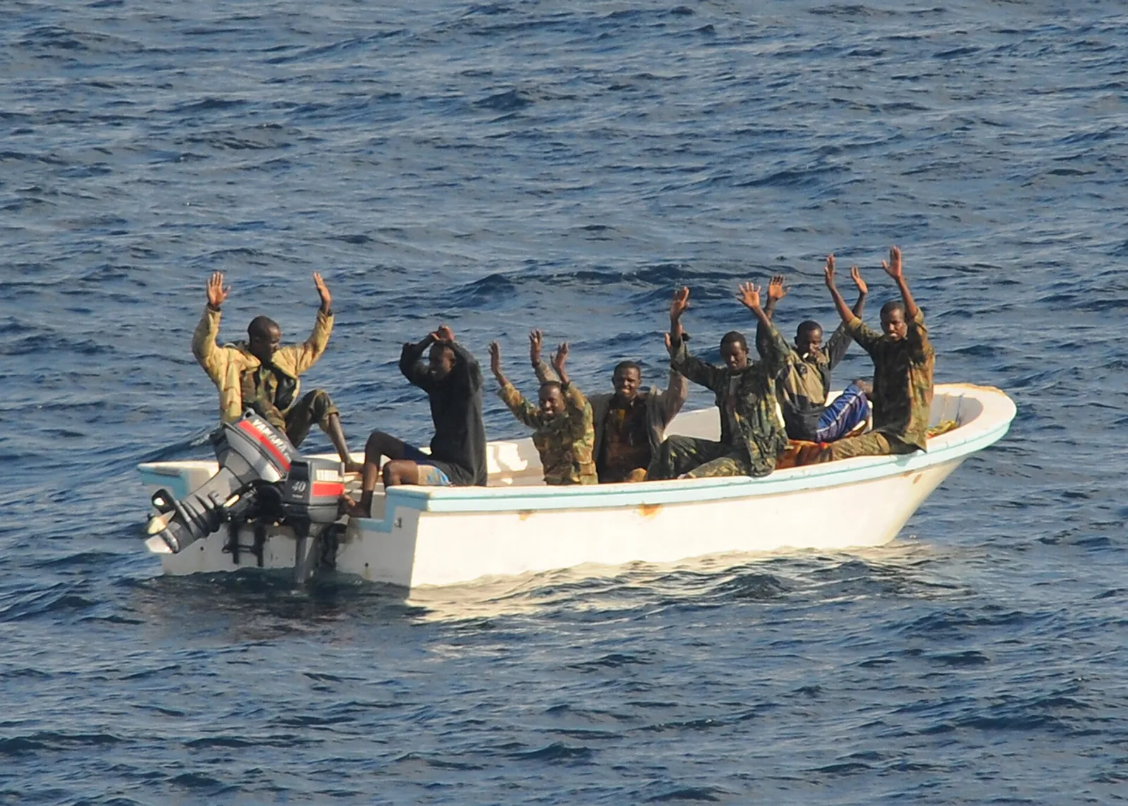 Suspected pirates raise their hands as an international naval force approaches their skiff off Somalia