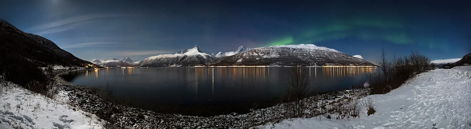 The aurora borealis glowing green above mountains in northern Norway