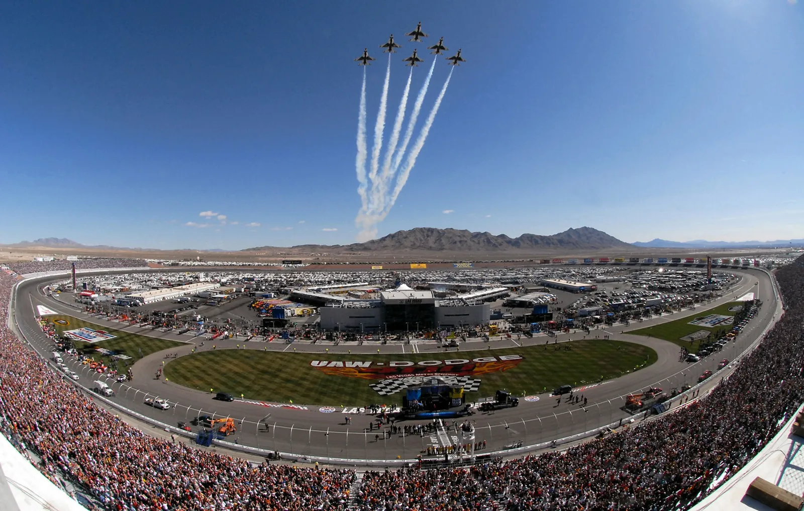 NASCAR stock cars racing in a pack on an oval track
