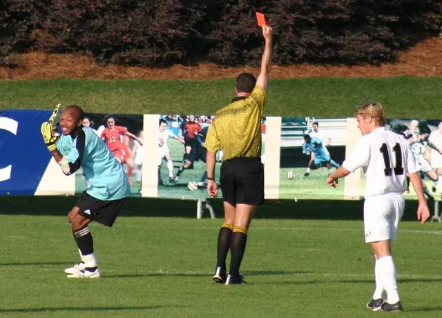 A football referee holding up a red card